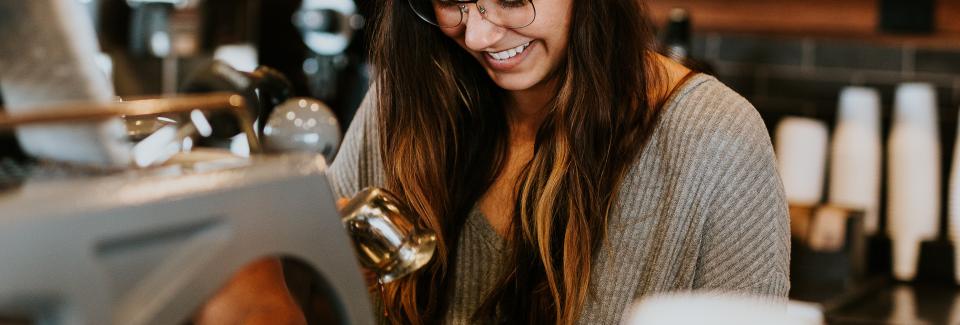 Happy student smiling while making coffee at a coffee shop